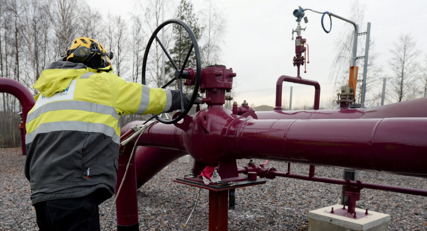 Person in yellow construction suit works on series of large pipes on a foggy day