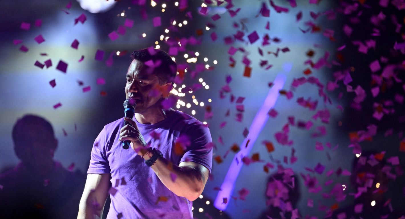 Photo of Daniel Noboa speaking at a rally with purple confetti falling around him.