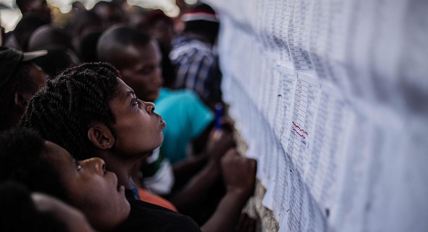 Internal Displaced Persons in the Bulengo Refugee Camp look at electoral posters and voters rolls for the camp representative elections in Bulengo, outside Goma, on December 16, 2024 ahead of the vote expected on December 18, 2024.