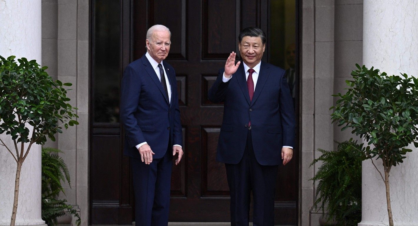 Biden and Xi standing in front of a set of doors, with Xi waving
