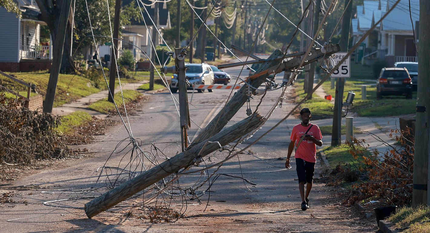 A person walks past downed power lines as people deal with the aftermath of Hurricane Helene on October 05, 2024 in Greenwood, South Carolina.