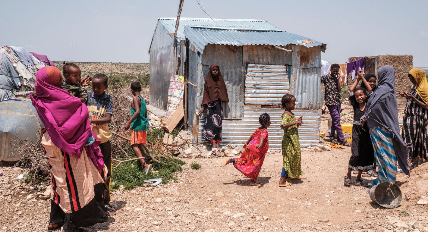 Photo of children outside a makeshift home in a settlement for people displaced by climate disasters in Somalia.