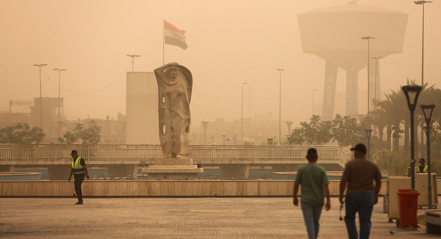 People walk in Al-Firdaws Square in Baghdad during a dust storm on May 5, 2025
