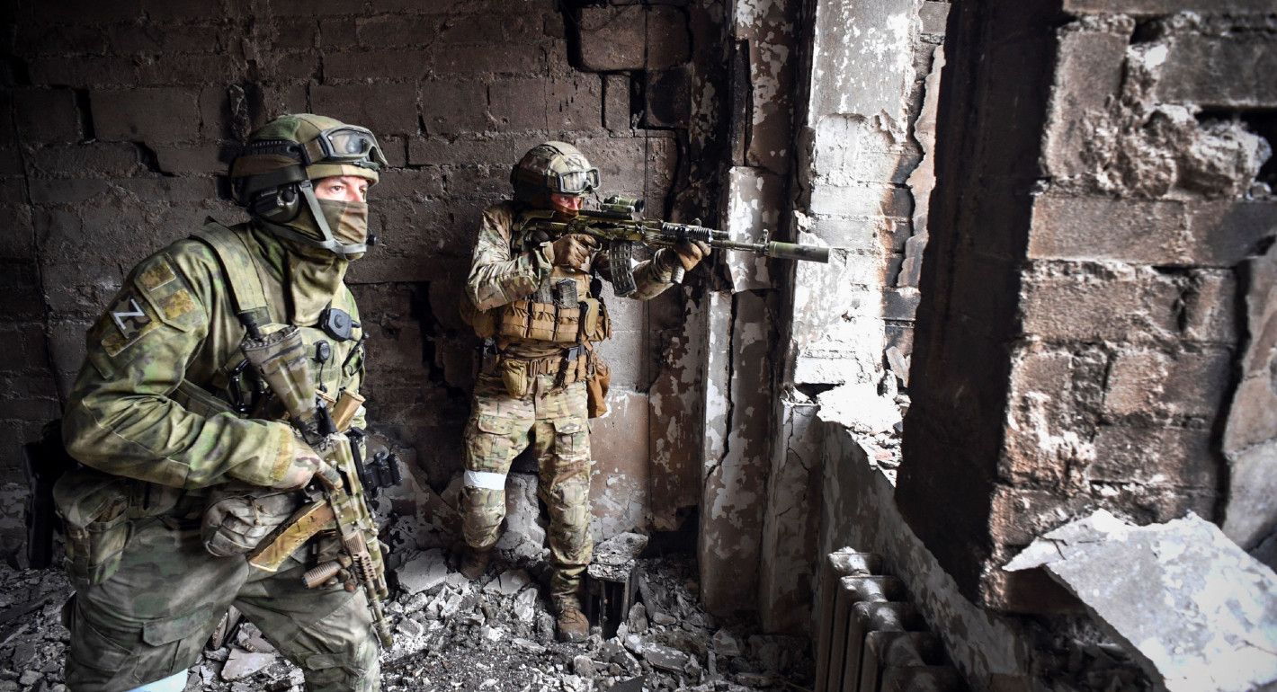 Photo of Russian soldiers pointing firearms out the window of a ruined building.