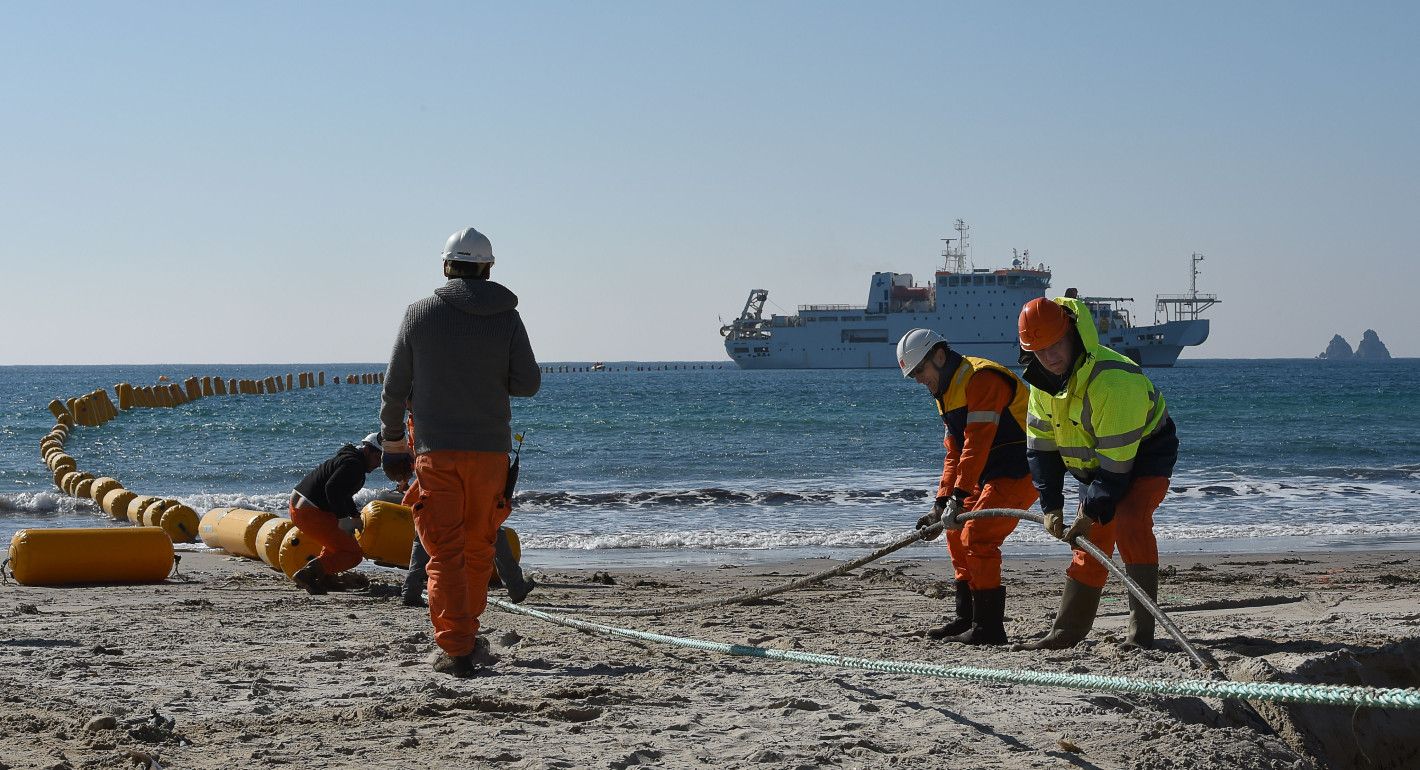 workers on a beach holding cables