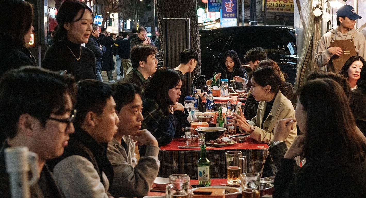 People eat dinner at a sidewalk terrace in Seoul on March 21, 2025