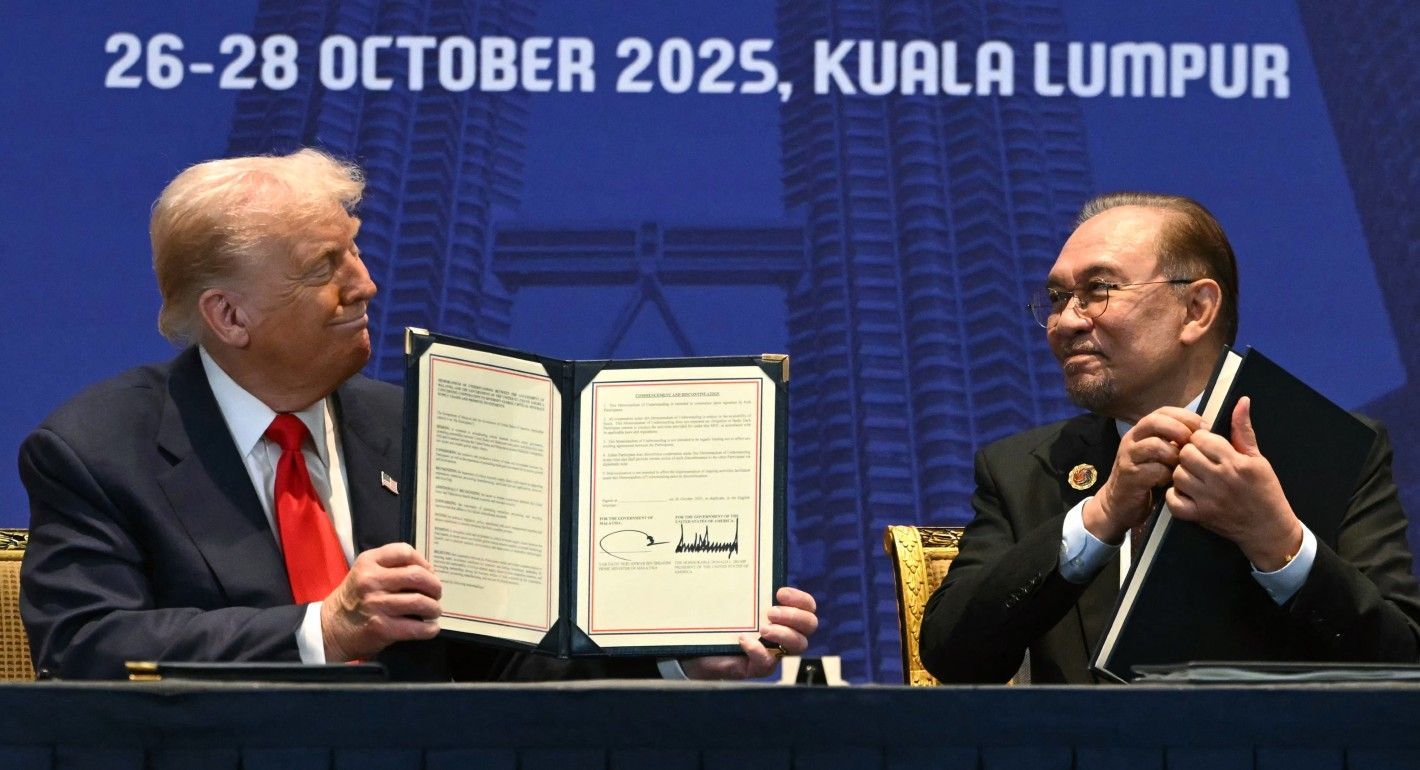 Trump and Ibrahim holding up official signed documents and smiling