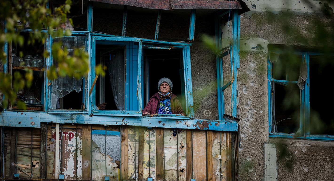 An elderly woman stands on the balcony of her damaged home following a shelling on the town of Bakhmut in Donetsk region, on October 25, 2022,