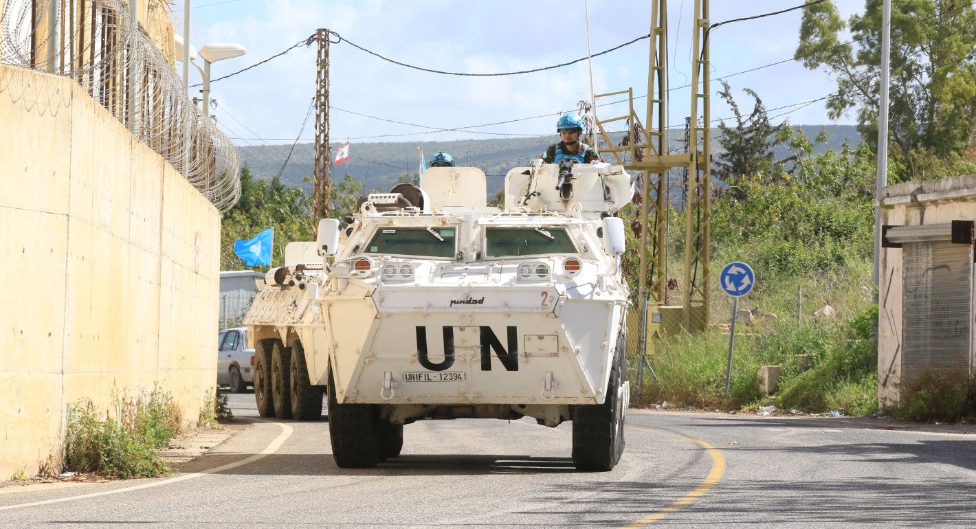 Tanks with UN on them drive down a road