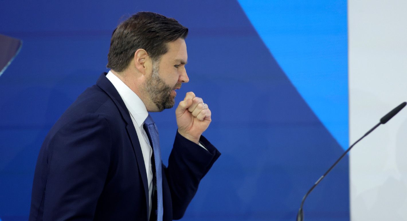 Photo of JD Vance (side profile) at a lectern in front of a blue background.